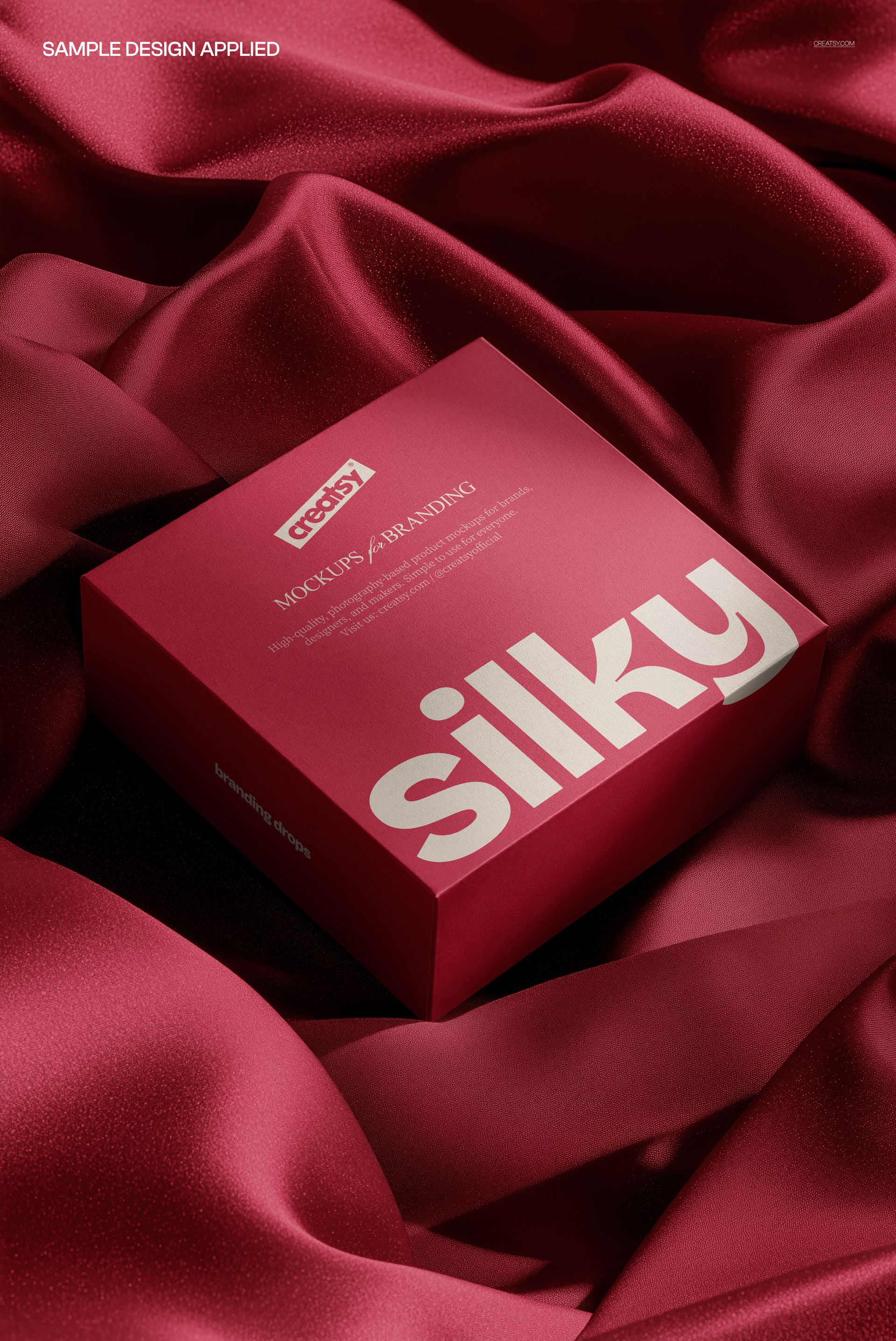 Red square box mockup resting on luxurious silky fabric, showing top and side with large printed lettering.