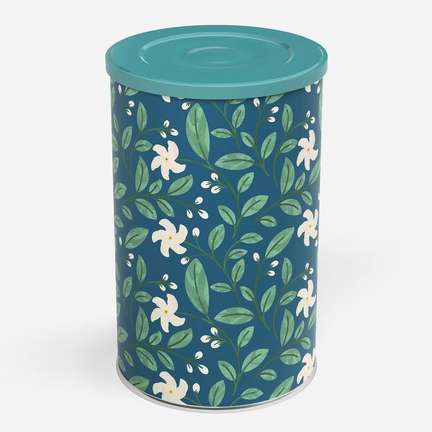 Tin canister mockup featuring a cylindrical container with a teal lid and a floral pattern of white flowers and green leaves on a dark blue background.