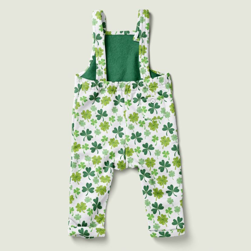Kids fleece dungarees mockup featuring a green and white clover leaf pattern, shown on a plain light background.