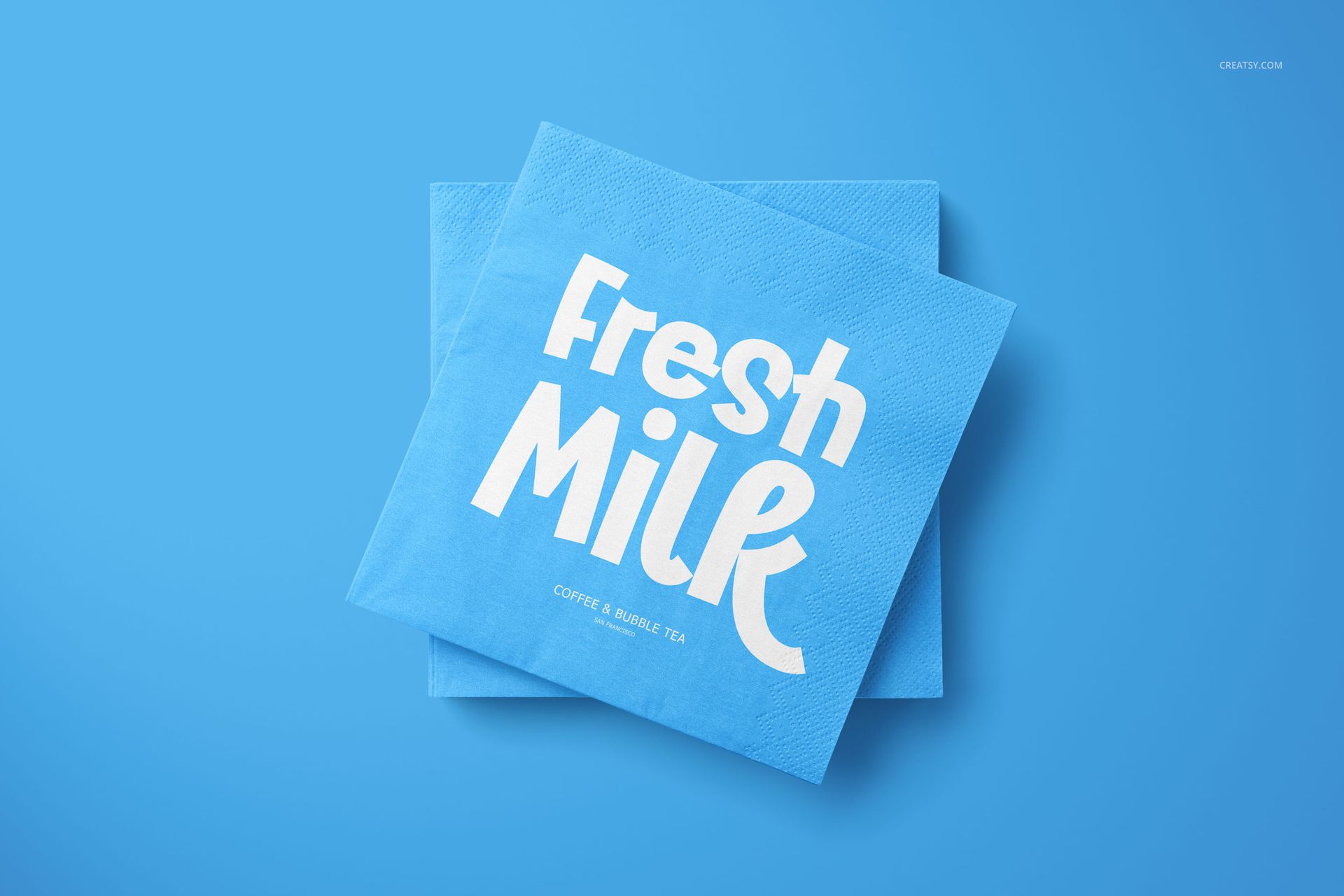 PSD mockup of two stacked blue napkins, one displaying white graphic text, set against a plain blue backdrop.