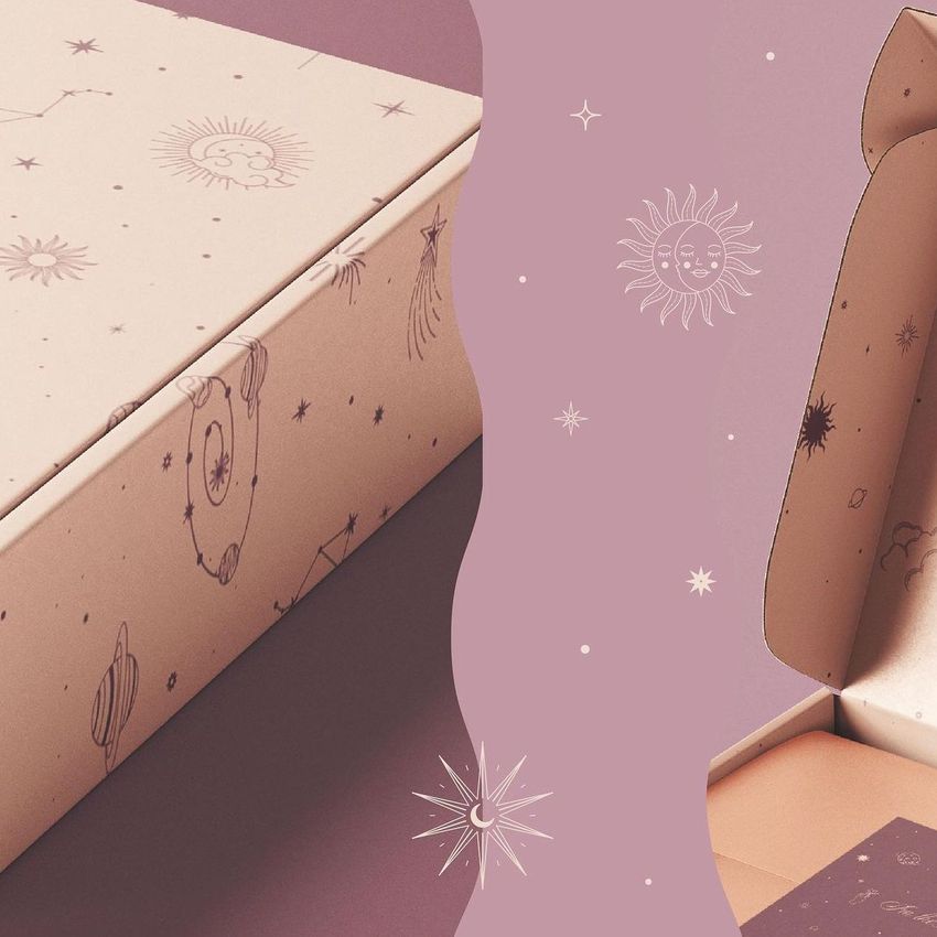 Mailing box mockup featuring a pastel pink box with celestial illustrations, shown closed and open on a mauve background.