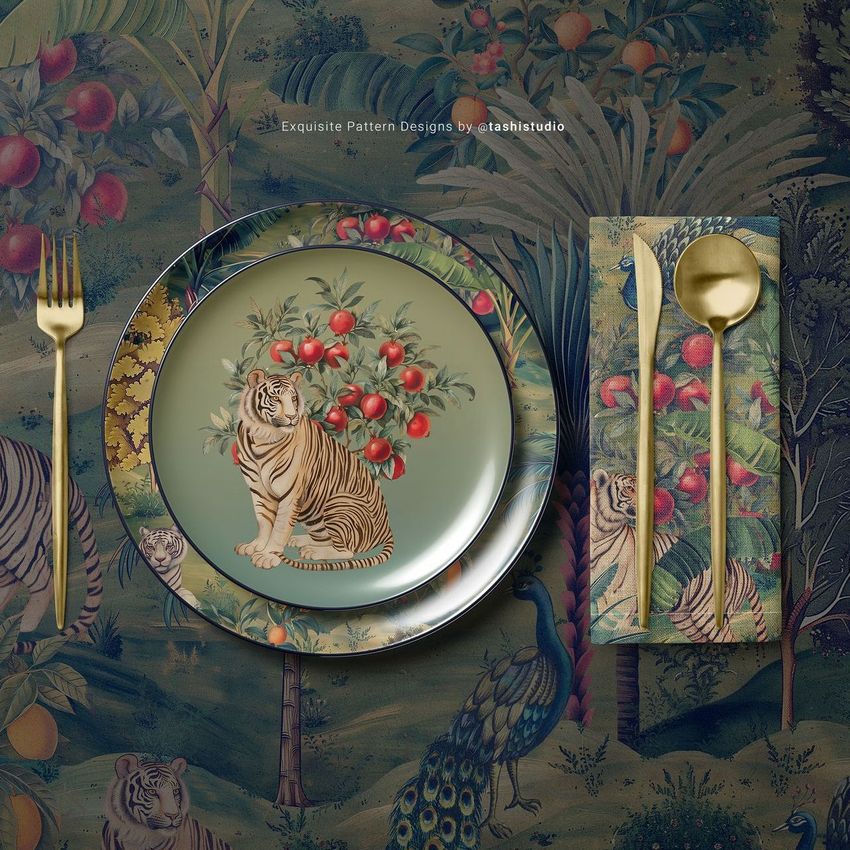 Placemat napkin plate mockup showing a tiger and fruit illustration on a plate, with gold cutlery on a patterned background.