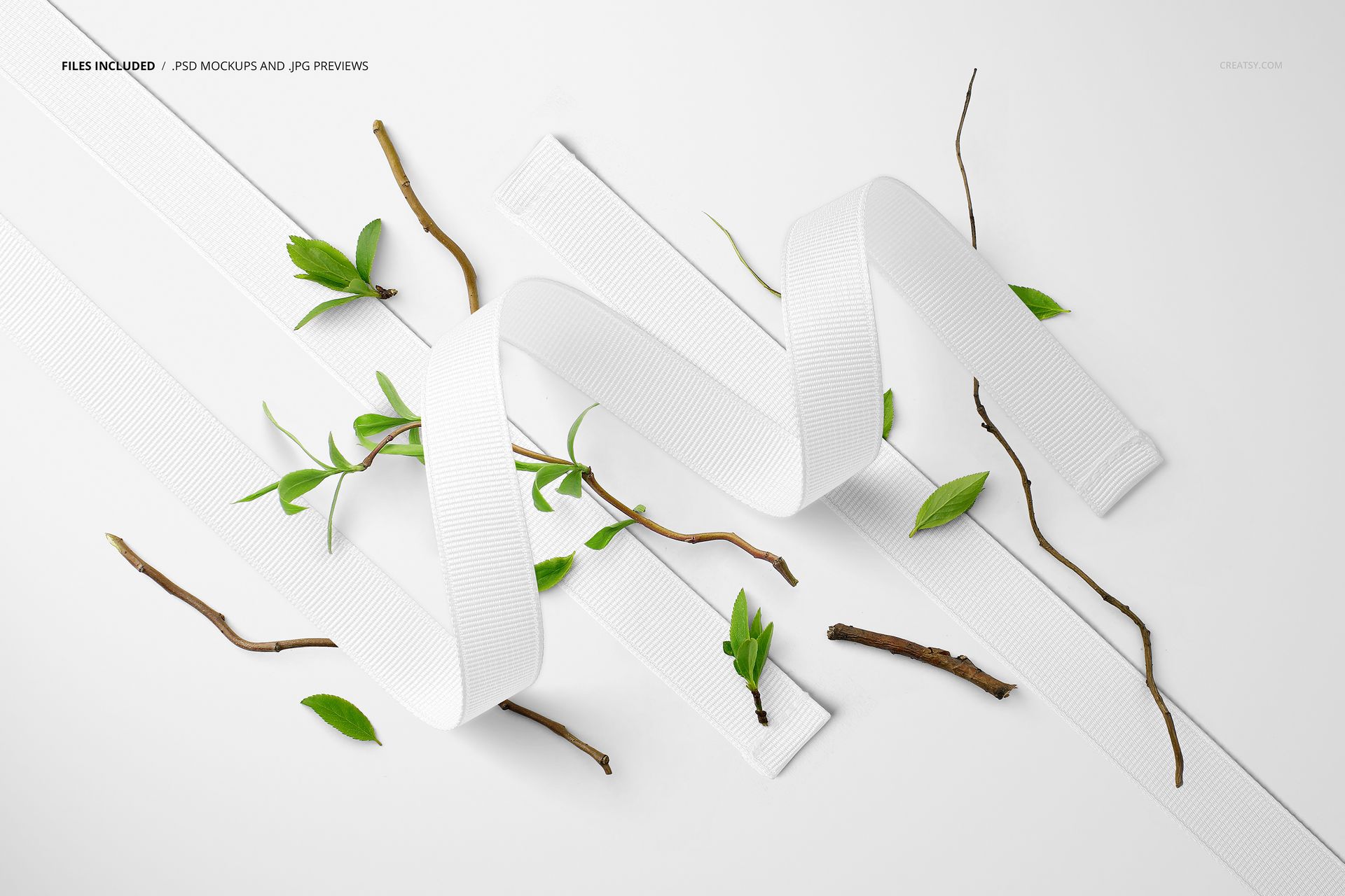 White grosgrain ribbons arranged on a flat surface with scattered green leaves and thin brown branches in a top view mockup.