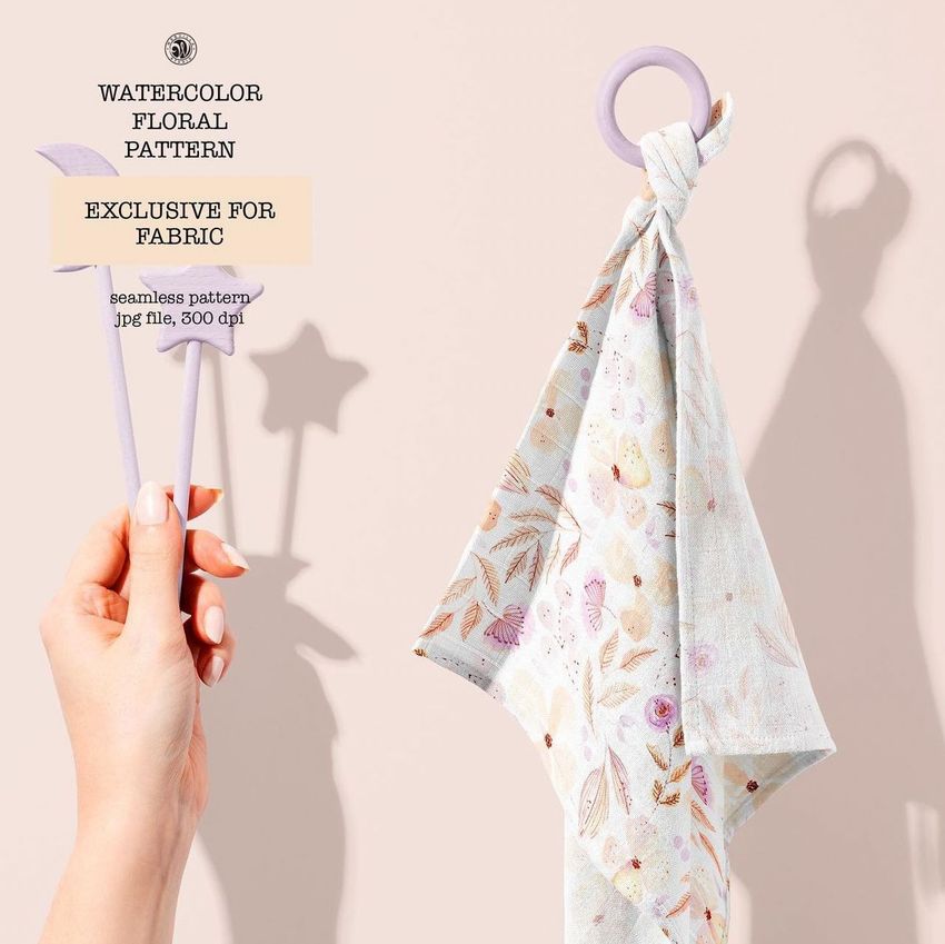 Muslin cloth wooden teether mockup featuring a pastel floral patterned fabric hanging from a wooden ring on a light background.