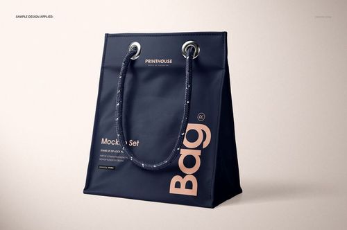Matte PVC reusable tote bag mockup in dark blue with large beige text, shown at a three-quarter front angle on a neutral background.