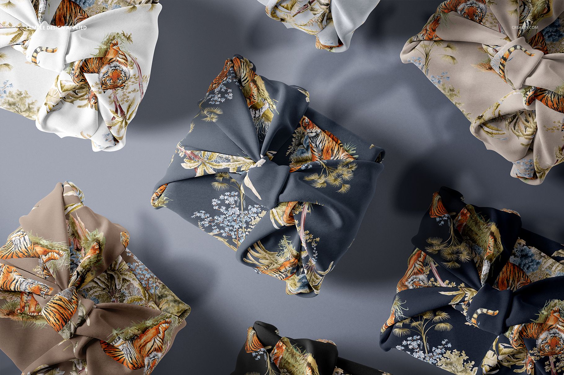 Fabric gift wrap mockup featuring multiple square packages wrapped in patterned cloth, viewed from above on a gray surface.