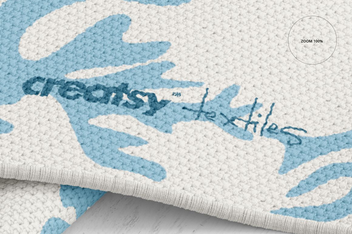 Close-up of a woven rug mockup displaying blue and white abstract shapes with visible textile texture details.
