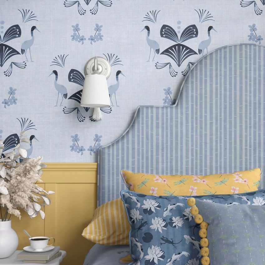 Bedroom mockup with a blue patterned headboard, floral and bird wallpaper, and pillows in yellow and blue botanical prints.