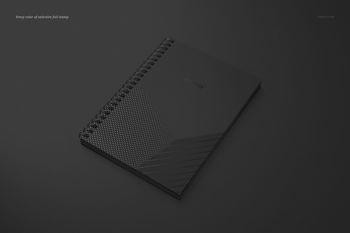 Black A5 spiral notebook mockup with square holes, matte and glossy geometric design, shown from a slight top angle.