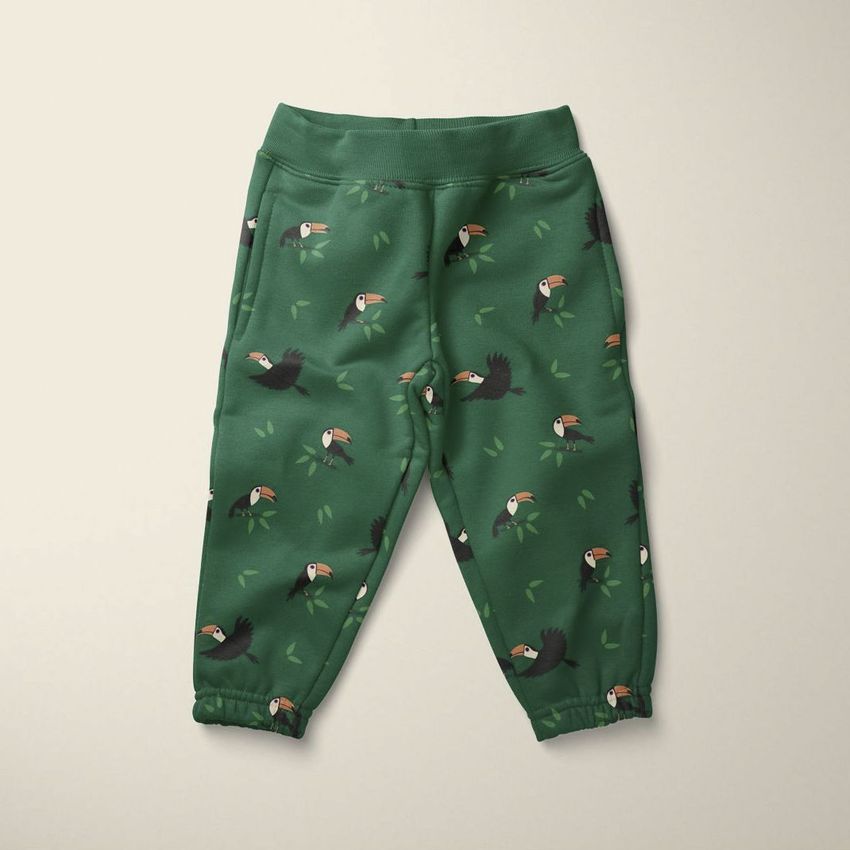 Kids fleece joggers mockup featuring green pants with a playful toucan bird pattern, displayed on a neutral background.