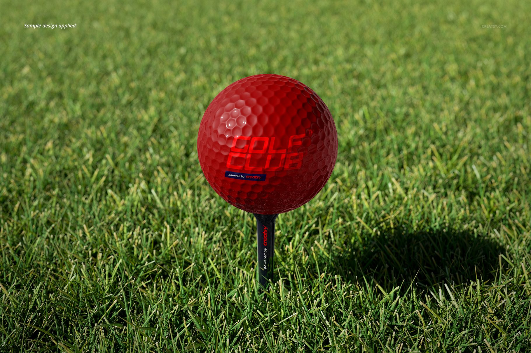 Golf ball and accessories mockup showing a vibrant red ball on a tee, surrounded by lush green grass.