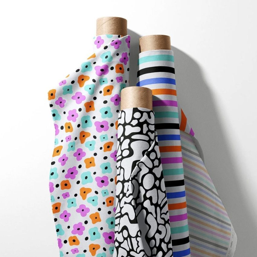 Fabric rolls mockup featuring four designs, including floral and abstract patterns, arranged upright on a white background.