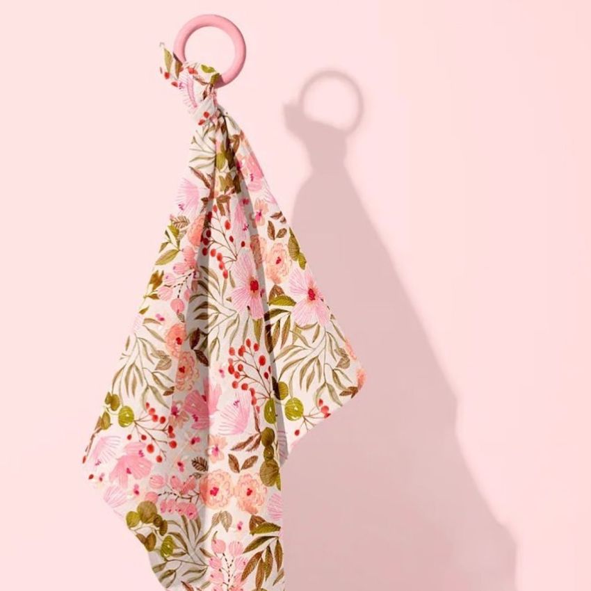 Muslin cloth wooden teether mockup featuring a floral patterned fabric hanging from a pink ring against a pale pink background.