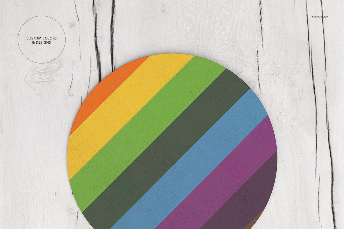 PSD mockup of a round coaster with bold diagonal rainbow pattern, presented on a white wood table, overhead angle.