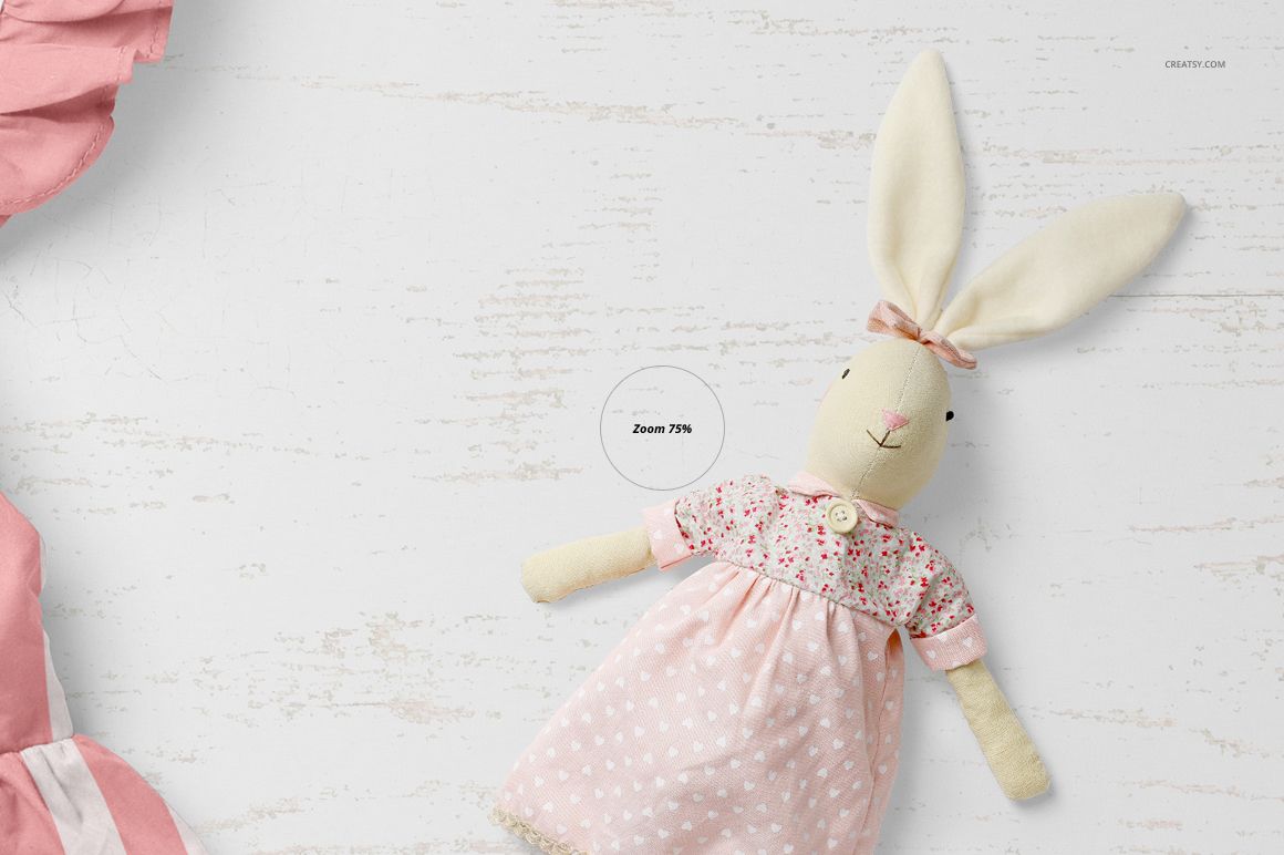 PSD mockup featuring a plush rabbit in a pastel pink dress with floral accents, displayed on a rustic white surface.