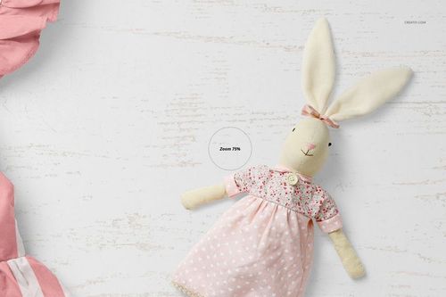 PSD mockup featuring a plush rabbit in a pastel pink dress with floral accents, displayed on a rustic white surface.