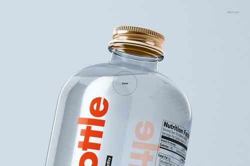 Mockup of a transparent glass bottle with a golden screw cap and visible label, angled against a light background.