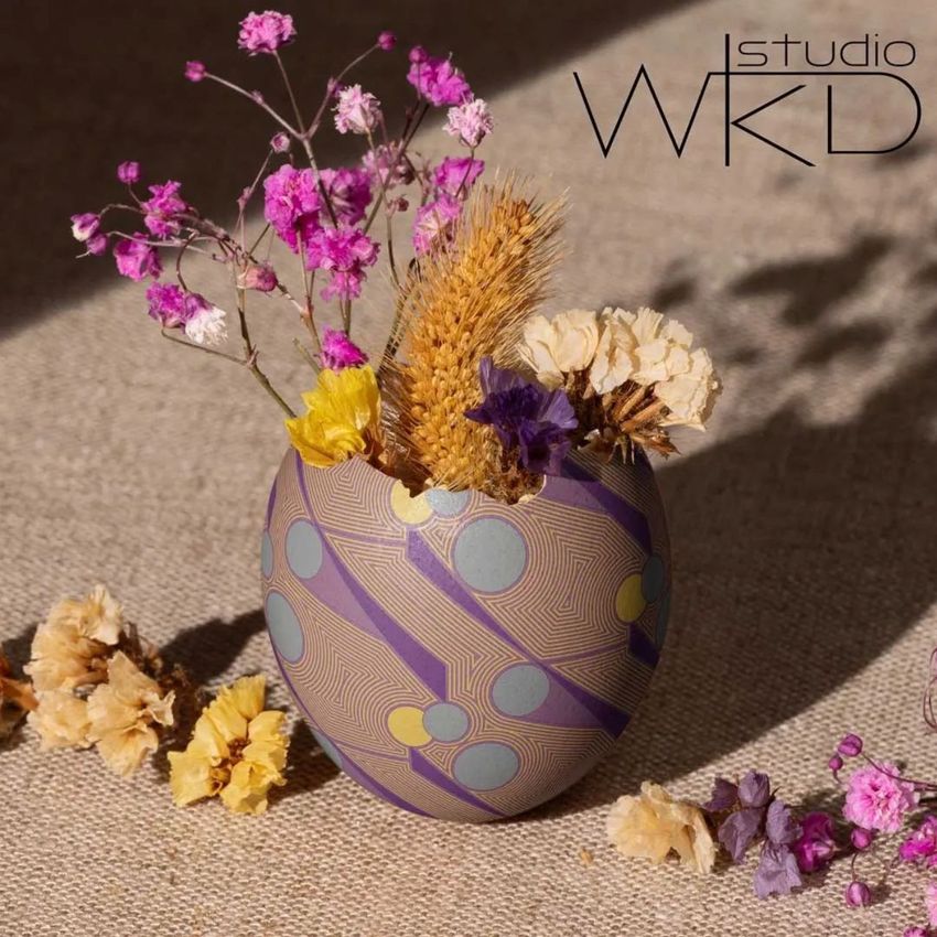 Painted Easter egg shell mockup used as a vase, holding dried flowers and wheat on a textured fabric surface with sunlight.