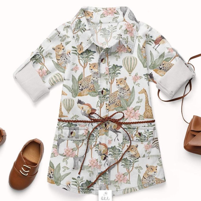 Baby jeans dress mockup with rolled sleeves, featuring a safari animal and foliage pattern, styled with brown shoes and a small bag on a white background.