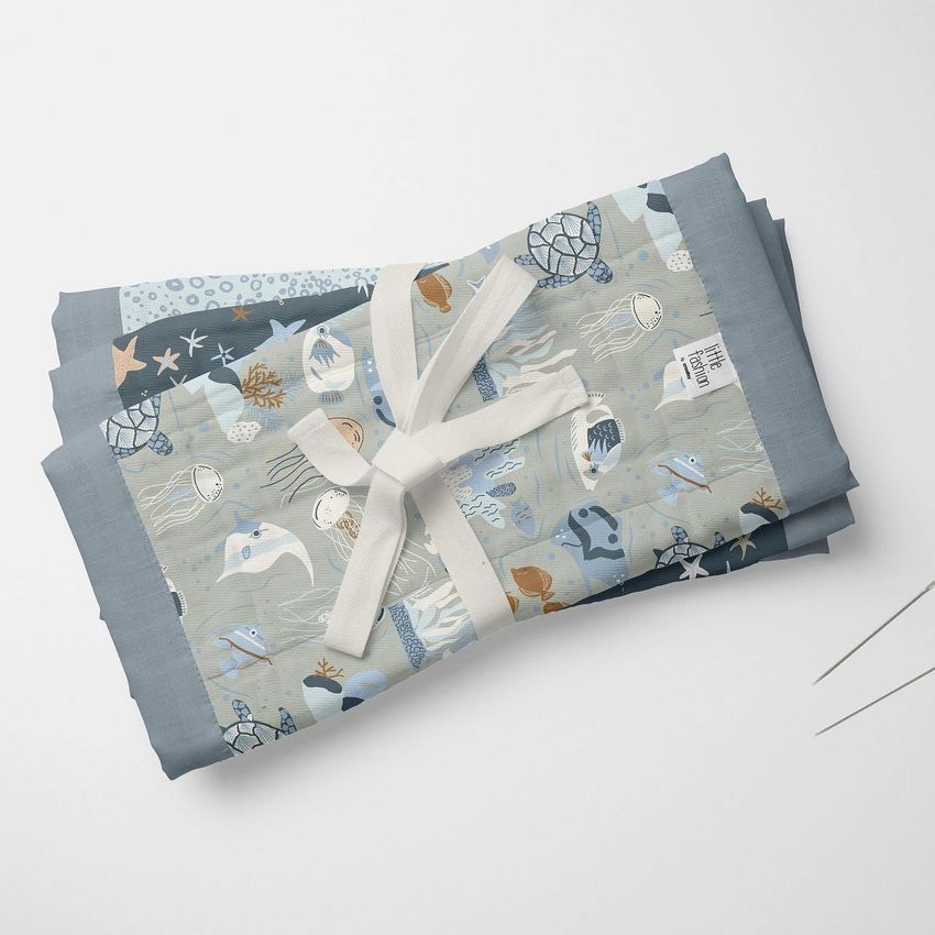 Burp cloth mockup featuring folded cloths with ocean-themed illustrations of sea creatures in blue and beige tones on a white surface.