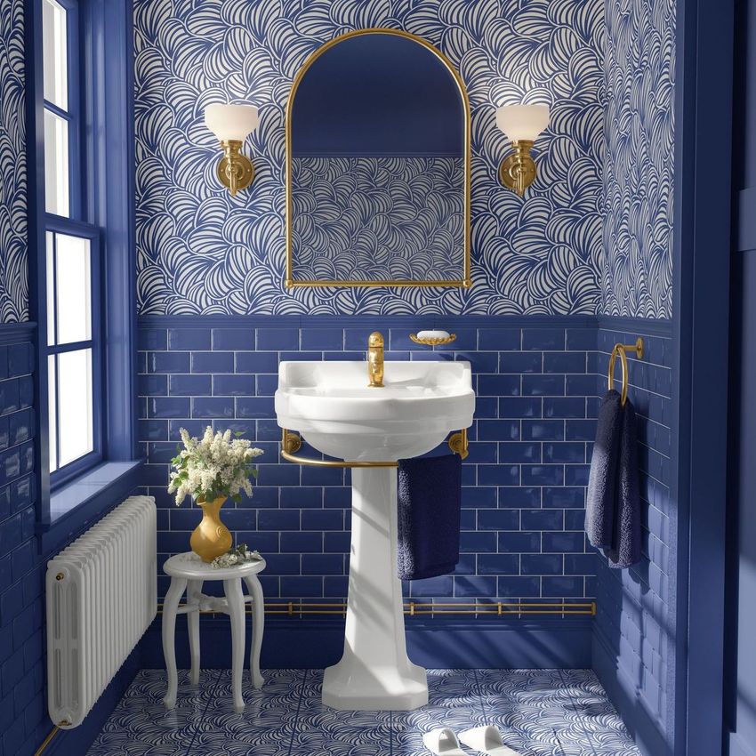 Vintage retro bathroom mockup featuring blue and white patterned wallpaper, a pedestal sink, gold fixtures, and a small table with flowers.
