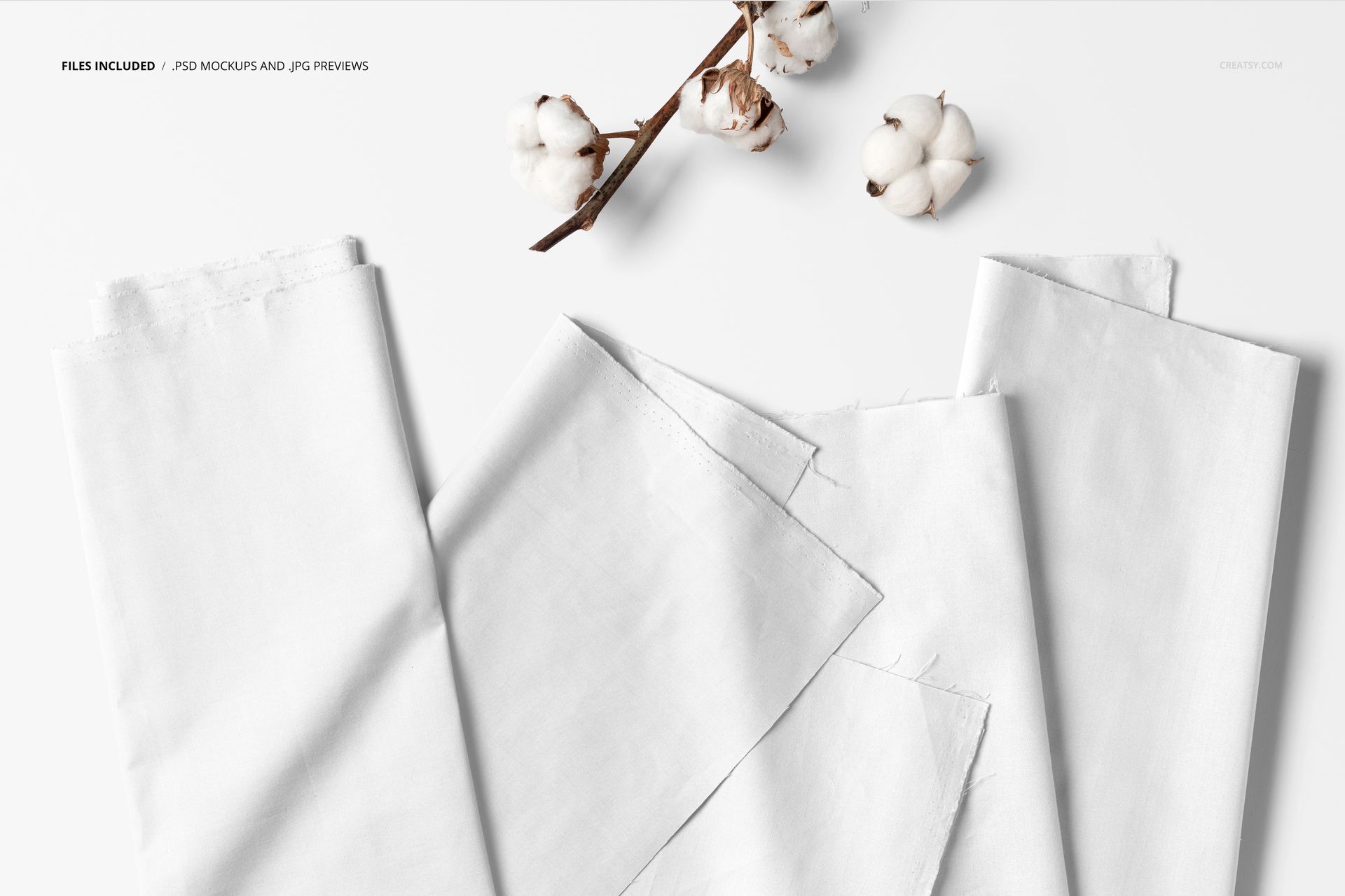 Folded white fabric pieces arranged on a flat surface with cotton branches, top view, fabric mockup scene.
