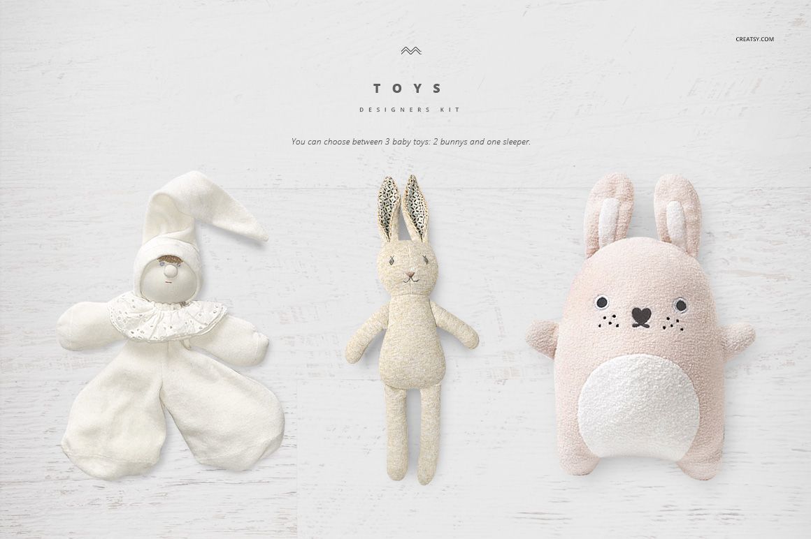Three baby toys displayed on a light wooden surface, including a bunny, a sleeper doll, and a plush rabbit pillow.