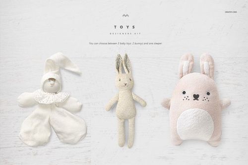 Three baby toys displayed on a light wooden surface, including a bunny, a sleeper doll, and a plush rabbit pillow.