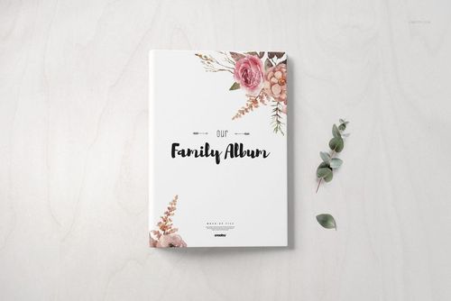 Front view of a hardcover family book mockup with floral illustrations on a light background and eucalyptus sprig beside.
