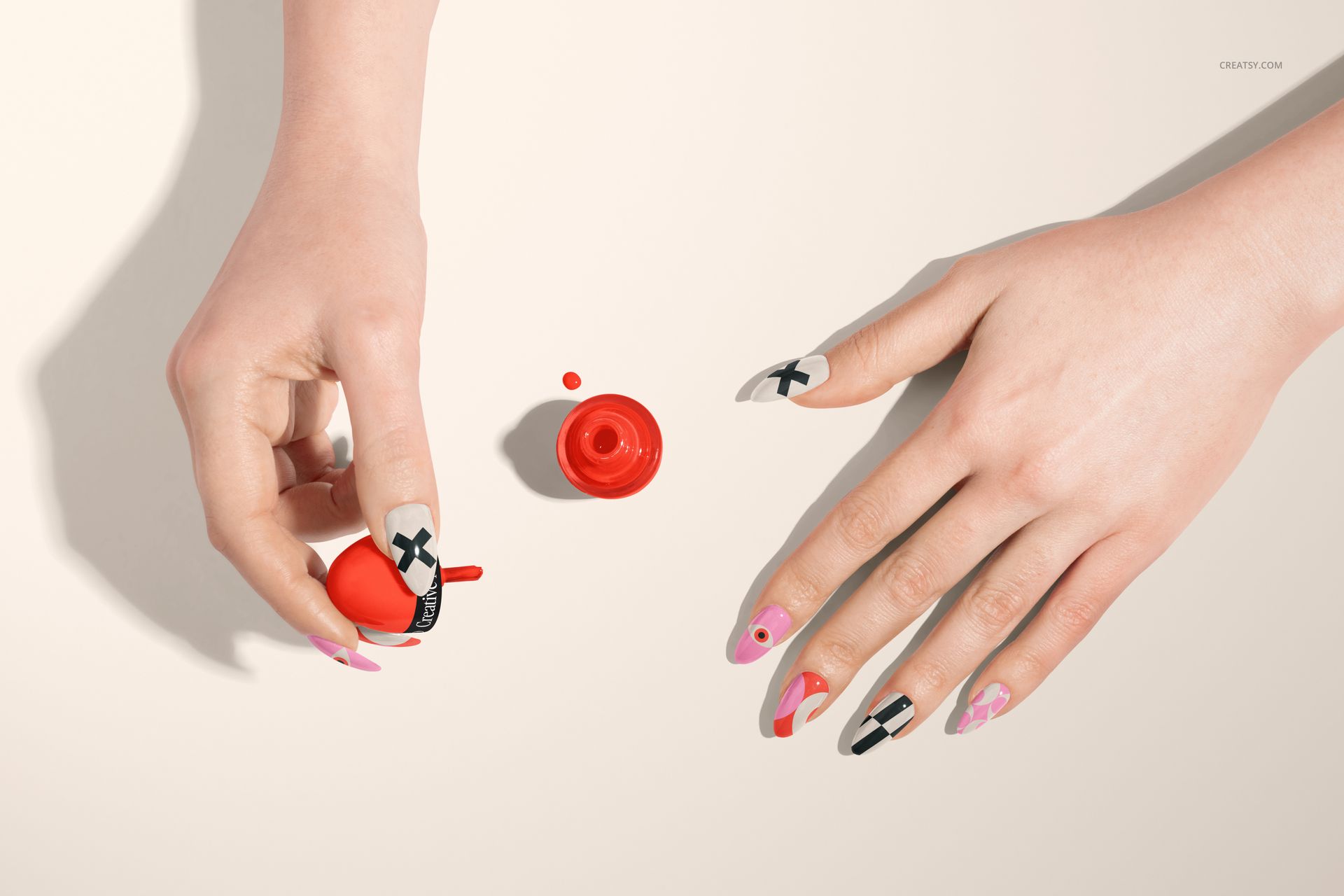PSD mockup showing hands with creative nail patterns and a red nail polish bottle, viewed from above on a neutral background.
