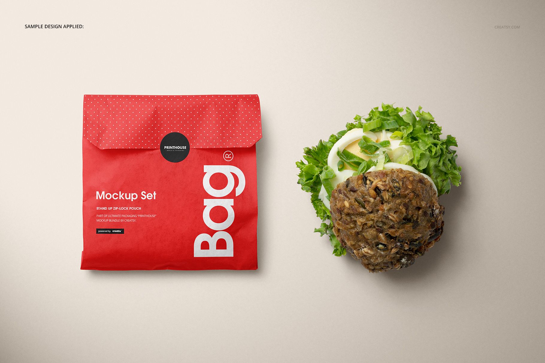 Sandwich snack paper bag mockup in red with a sticker seal, shown beside an open sandwich with leafy greens.