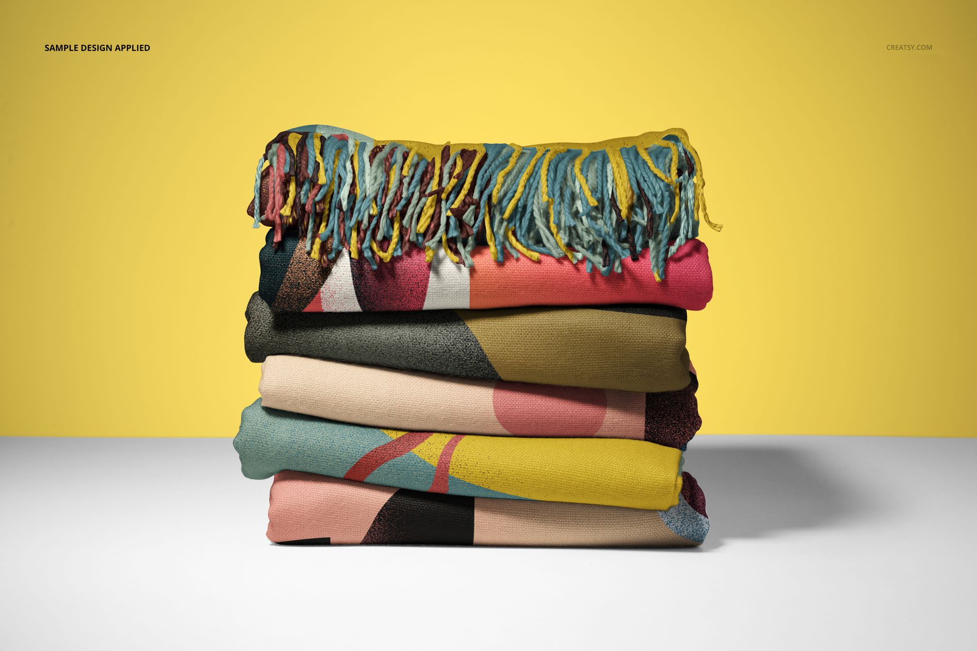 Front view of stacked blankets with decorative fringe edges, displaying multicolor abstract prints in a PSD mockup scene.