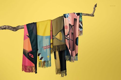Tassel fringe blankets featuring bold geometric designs hang on a branch, shown in a PSD mockup with a yellow backdrop.