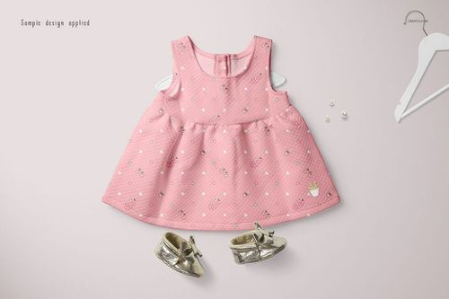Layered PSD mockup featuring a sleeveless pink baby dress, gold shoes, and small decorative pearls on a pale surface.