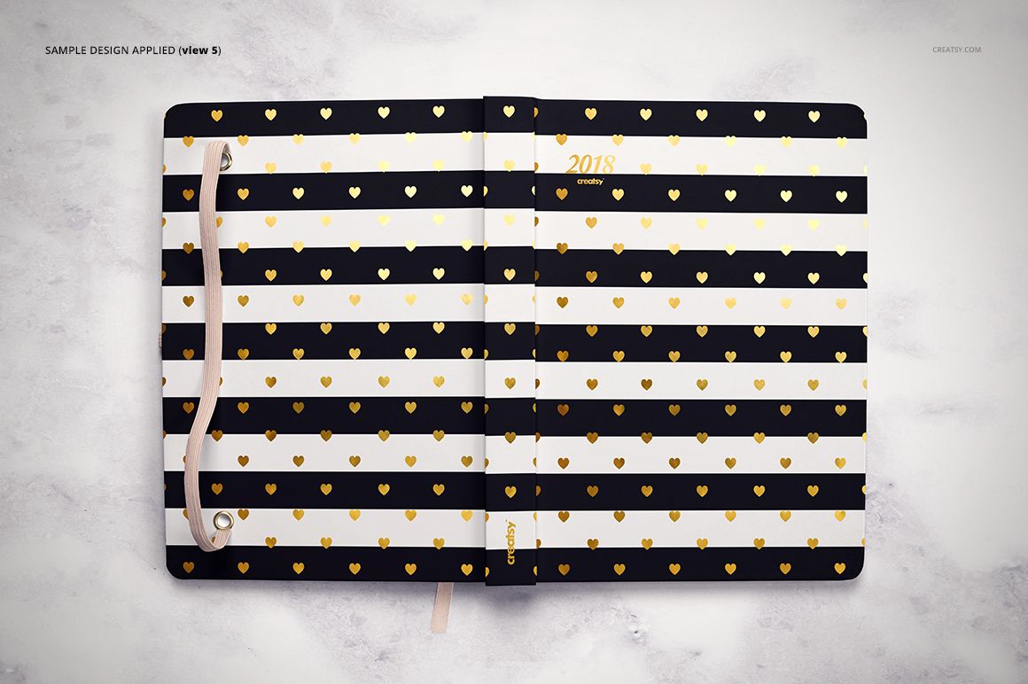 Top view of a planner mockup featuring alternating black and white stripes with gold hearts, lying open on a light background.