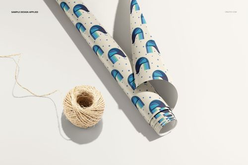 Gift wrapping paper mockup with a modern blue and teal design, partially unrolled and placed next to string on a neutral surface.