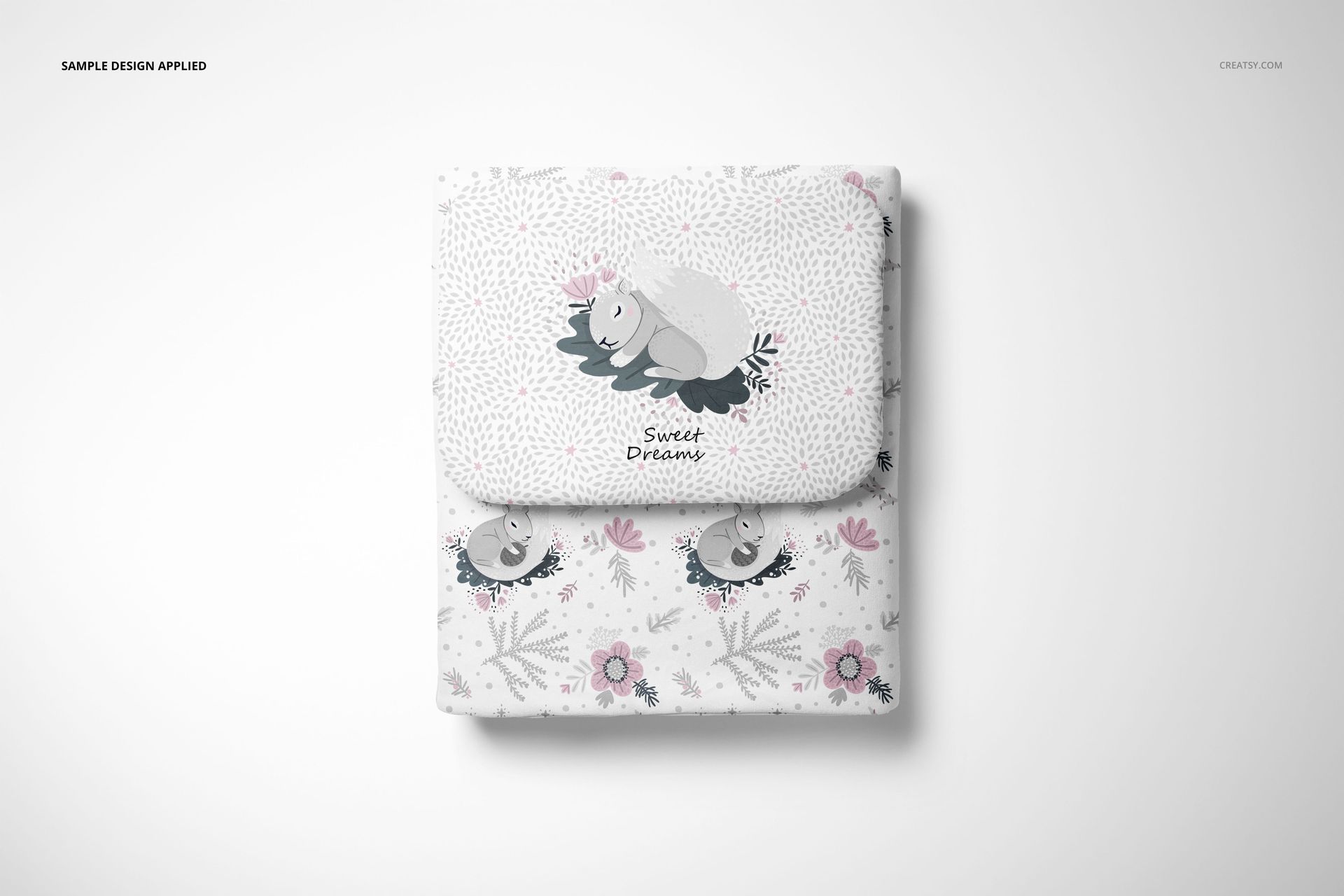 Top view of a baby bedding set mockup, including a pillow and quilt with whimsical animal and floral designs.