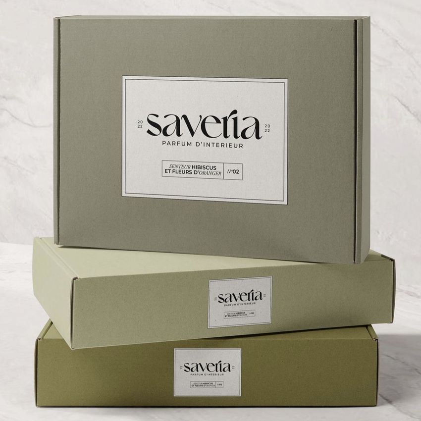Two mailing box mockups in muted green tones are stacked on a light surface, each featuring minimalist labels with text.