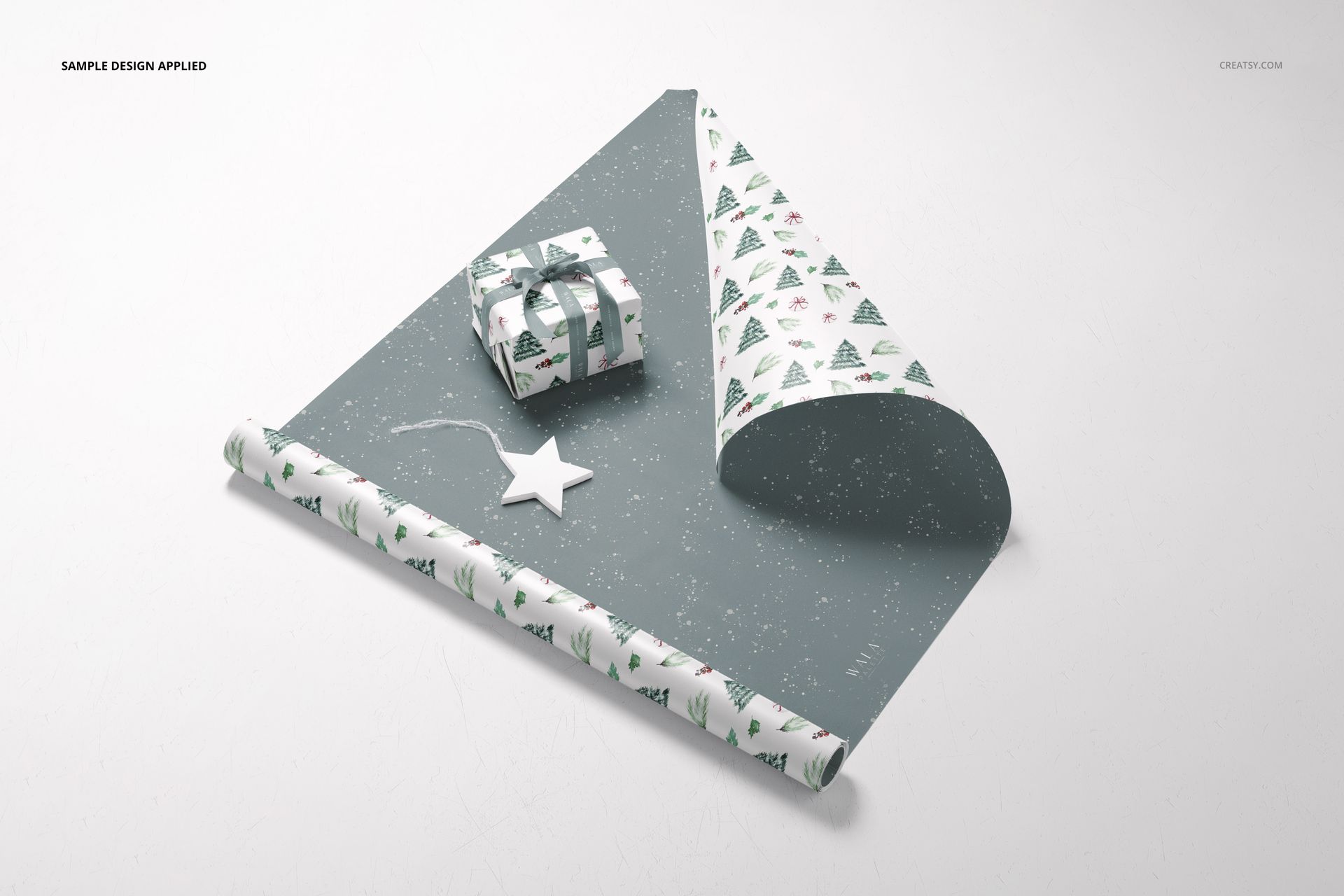 Gift wrapping paper mockup featuring a partially unrolled sheet with festive tree patterns, a wrapped box, and a star ornament on a light surface.