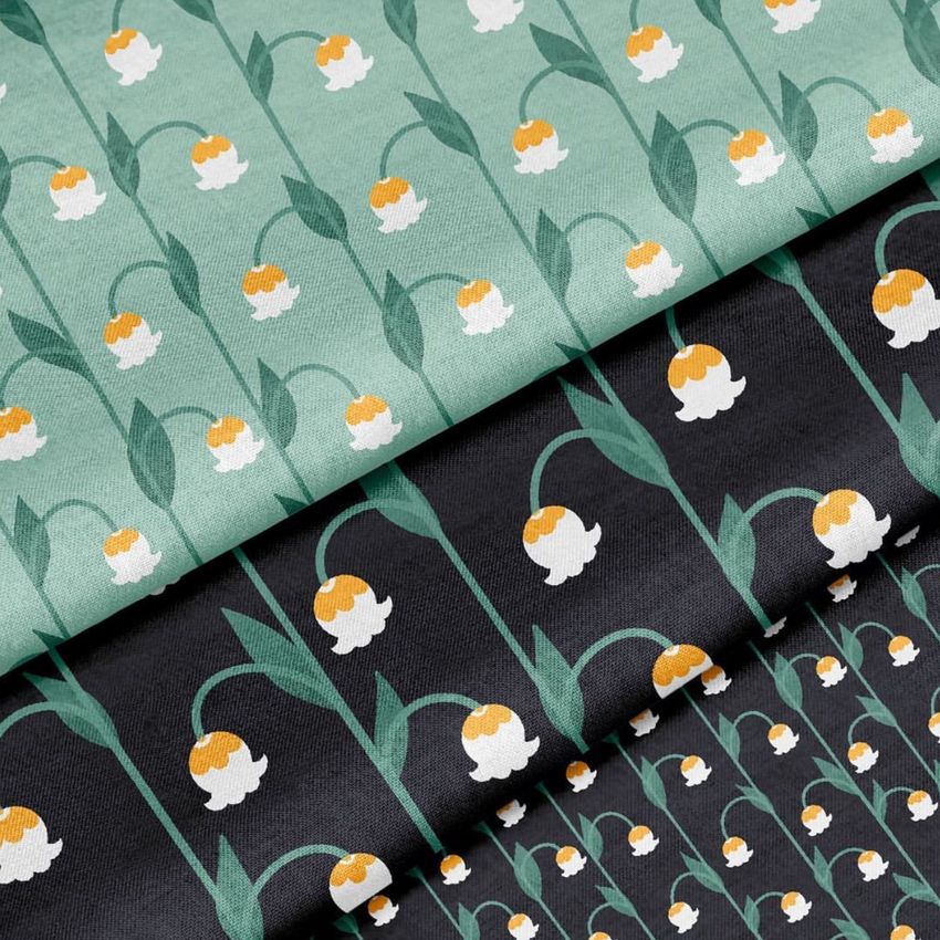 Cotton fabric mockup featuring three folded textiles with a repeating lily of the valley pattern in green, black, and teal colors.