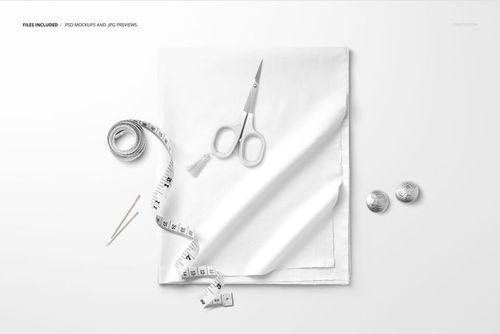 Top view of a folded cotton fabric mockup with sewing tools including scissors, tape measure, and buttons arranged around.