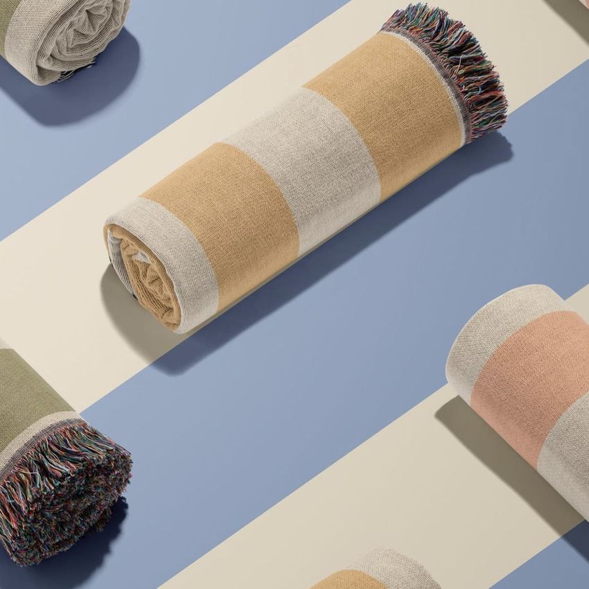 Jacquard fringed woven throw blanket mockup showing several rolled blankets with wide horizontal stripes on a striped surface.