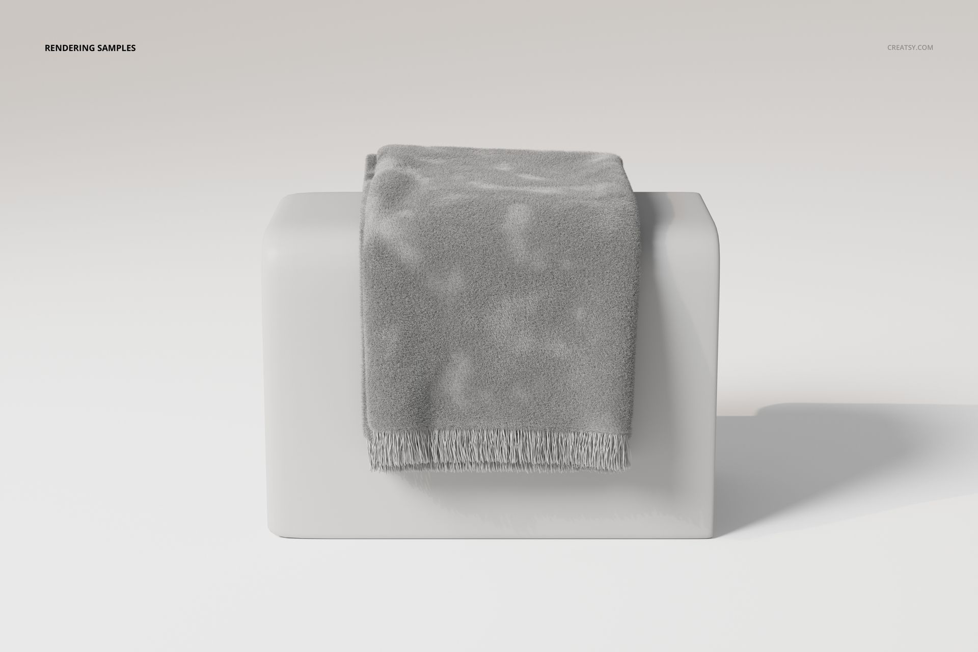 Gray fringe blanket draped over a rectangular white pedestal, shown from a front angle on a minimal background.