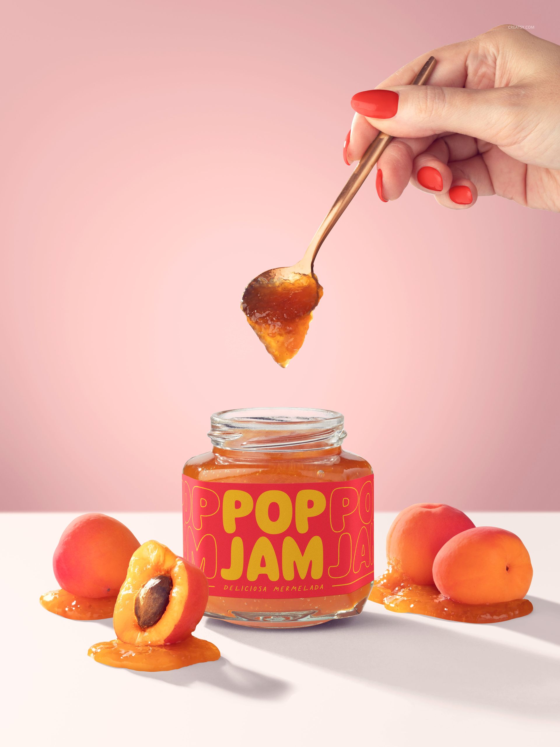 Apricot jam jar mockup with spoon held above, sliced apricots and spilled jam arranged on a light pink background.
