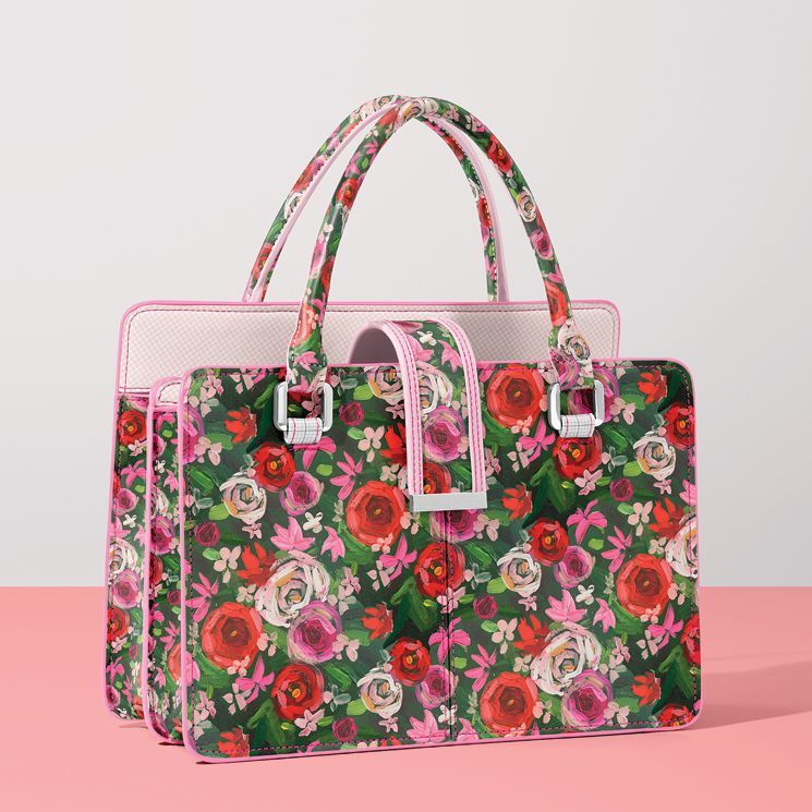 Leather handbag mockup featuring a floral pattern with red, pink, and white flowers on a green background, displayed on a pink surface.