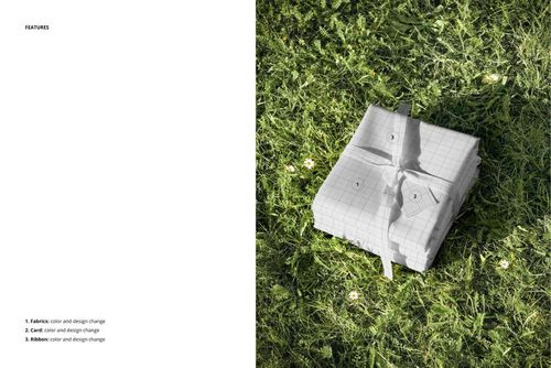 PSD mockup showing a pile of grid-patterned fabric tied with ribbon, lying on grassy ground with scattered daisies.