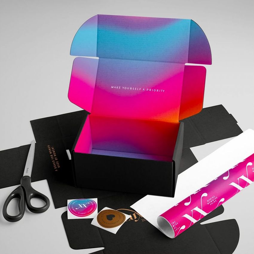 Mailing box mockup with a vibrant gradient interior in pink, blue, and purple tones, surrounded by packaging materials and scissors.