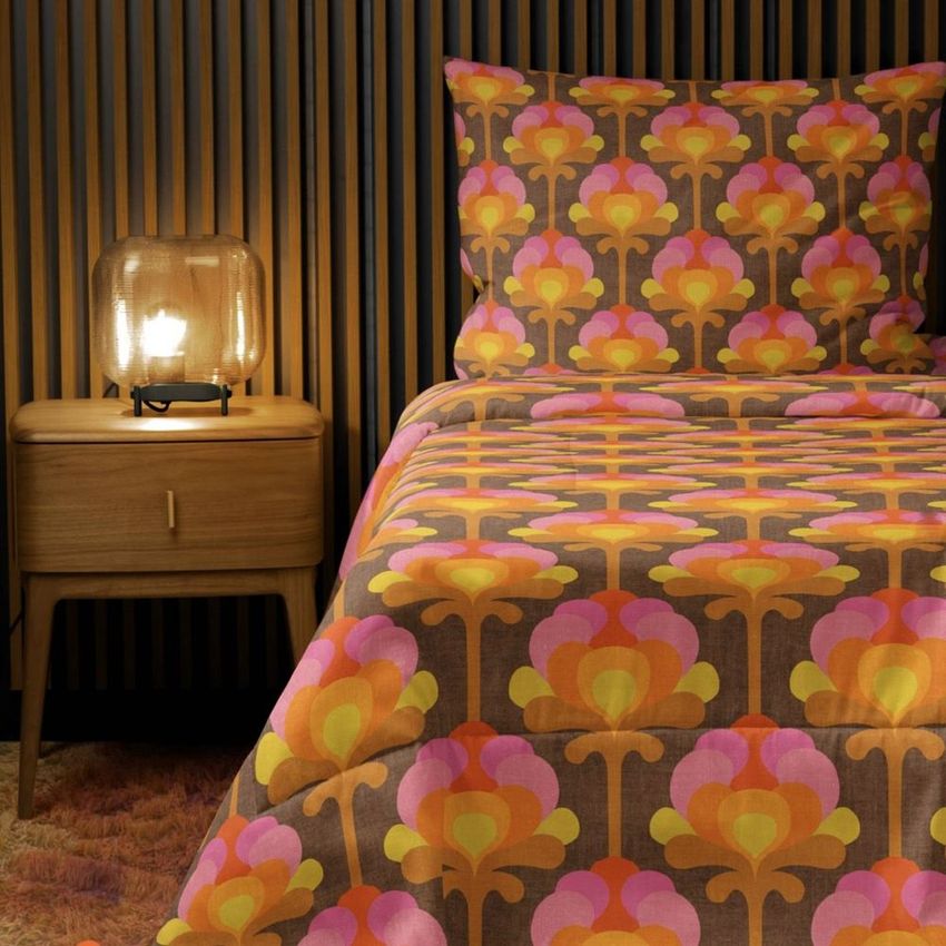 Microfiber comforter mockup featuring a retro floral pattern in orange, pink, and brown on a bed with matching pillowcase.