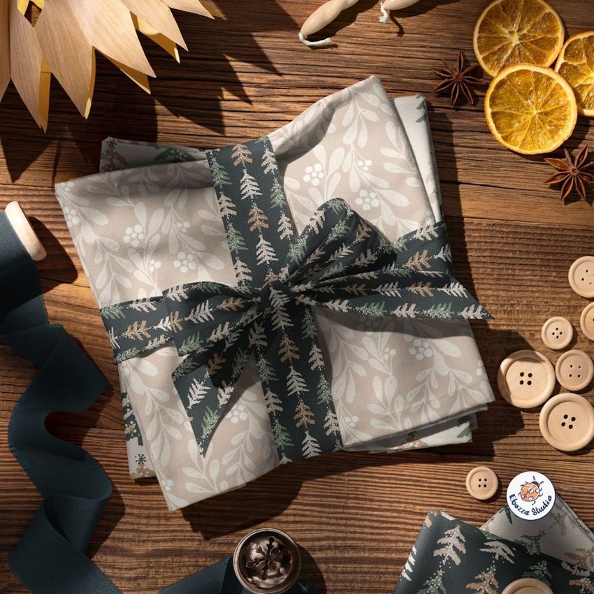 Christmas-themed folded fabric mockup with a decorative ribbon, buttons, dried orange slices, and spices on a wooden surface.