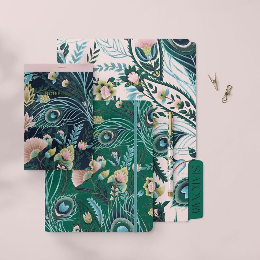 Stationery set mockup featuring notebooks, a folder, and accessories with green and pink floral patterns on a light surface.
